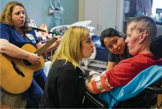  ?? Mark Mulligan / Houston Chronicle ?? Music therapist Amy Marroquin, from left, Danielle McNicoll and speech therapist Carissa Ngo encourage Nick Tullier to make vowel sounds in a therapy session.