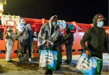  ?? AP ?? Migrants, wearing face masks to help curb the spread of Covid-19, disembark from a tug in Lampedusa yesterday. Many migrants are sleeping on the port’s dock because its migrant housing centre, which had been empty until Monday, is full.