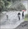  ??  ?? Neighbours walk under the rain on a washed-out road in Costa Rica.