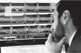  ?? Richard Drew / Associated Press ?? A specialist watches screens at the New York Stock Exchange. An analysis found that the gap between “adjusted” profits and bottom-line earnings has widened.