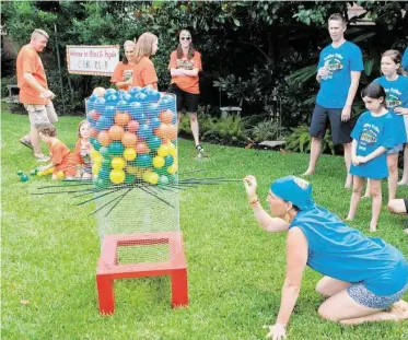  ?? R. Clayton McKee photos / For the Chronicle ?? Liz Goodman pulls a stick from the hive during a game at Cousin Camp, Frank and Lynda Bain’s backyard celebratio­n for their kids and grandkids. The object here was to remove sticks from the bottom of the “hive” without letting the balls or wasps fall...