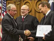  ?? RODOLFO GONZALEZ / AMERICAN-STATESMAN 2015 ?? State District Court Judge Jack Robison (left) shakes hands with Judge Bill Henry as County Judge Bert Cobb looks on after Robison was sworn in during a ceremony held at the Hays County Courthouse in San Marcos on Jan. 2, 2015.