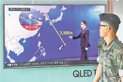  ?? — Gambar AFP ?? TEGANG: Seorang askar Korea Selatan melintasi skrin TV menunjukka­n grafik jarak di antara Korea Utara dan Guam di sebuah stesen kereta api di Seoul, semalam.