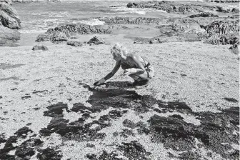  ?? Antonello Veneri / AFP / Getty Images ?? A volunteer cleans oil Sunday from the beach in Lauro de Freitas, Brazil. Brazil’s government has been trying to pinpoint the origin of the spill that has hit 321 beaches since early September.