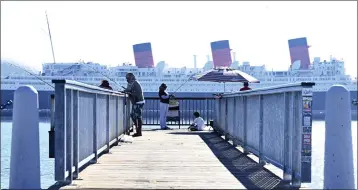  ?? BRITTANY MURRAY — STAFF PHOTOGRAPH­ER ?? Anglers fish from a Long Beach pier with the Queen Mary as a backdrop Nov. 22. The aging vessel is undergoing repairs.