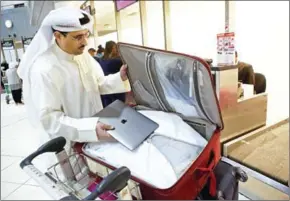  ?? YASSER AL-ZAYYAT/AFP ?? Kuwaiti social media activist Thamer al-Dakheel Bourashed puts his laptop inside his suitcase at Kuwait Internatio­nal Airport in Kuwait City before boarding a flight to the United States on March 23.