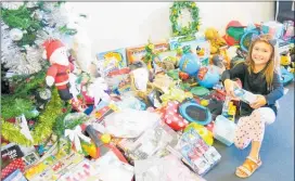  ??  ?? Five-year-old Chloe Robins adding to the pile of gifts underneath the Advertiser’s Community Christmas tree.