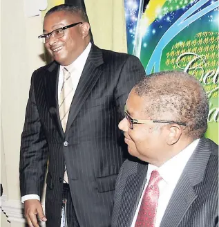  ??  ?? In this 2012 photo, brothers Konrad Mark Berry (standing) and Christophe­r Berry are seen at Mayberry’s annual general meeting in Kingston. A company owned by the brothers has been contracted to manage Mayberry’s investment portfolio.