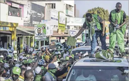 ?? Photo: Marco Longari/afp ?? Support: An assistant to Danny Yenga (second right), a candidate for the ruling Patriotic Front, hands out a cloth with a picture of President Edgar Lungu during a campaign parade in Lusaka.