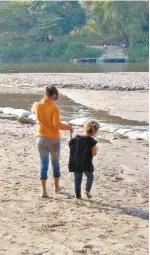  ??  ?? Antes de alejarse del río Suchiate, Angeli lleva a su hermana para que toque el agua.