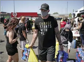  ?? BRIAN PETERSON — STAR TRIBUNE VIA ASSOCIATED PRESS ?? Minnesota Vikings NFL football player Kyle Rudolph helps a woman carry items to her car at the “Change Starts with Me” food and household supply giveaway outside a Cub Foods store in Minneapoli­s on June 5.