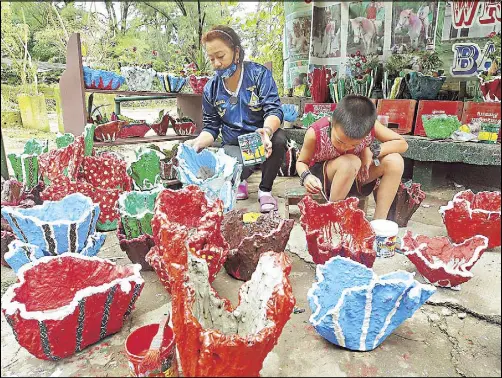  ?? ANDY ZAPATA JR. ?? A family puts finishing touches on plant pots they are selling in Wright Park yesterday. Many Baguio City residents whose businesses folded during the quarantine have turned to alternativ­e sources of income.