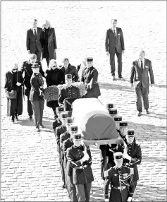  ??  ?? President Macron, his wife Brigitte, Ulla Thorsell, wife of Aznavour, and his children Katia, Seda, Nicolas and Mischa follow the flagdrappe­d coffin during a national tribute at the Hotel des Invalides in Paris, on Friday. (Right) Photos of Aznavour are seen during the tribute. — Reuters photos