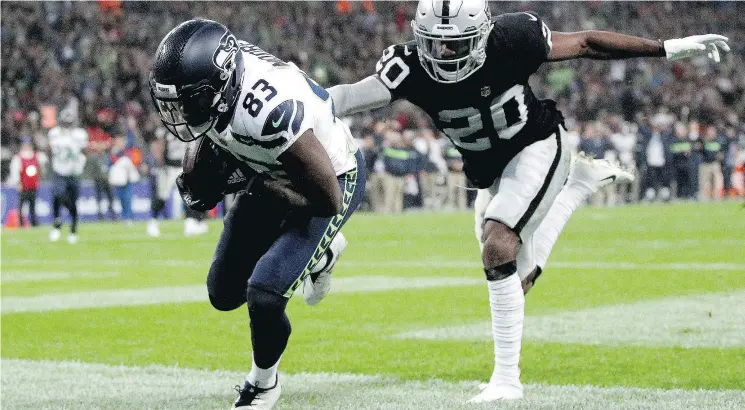  ?? JAMES CHANCE/GETTY IMAGES ?? David Moore of Seattle Seahawks scores a touchdown as Daryl Worley of the Oakland Raiders tries to tackle him at Wembley Stadium on Sunday.