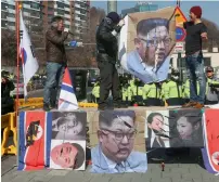  ?? AP ?? A S. Korean protester uses a knife to tear a portrait of N. Korean leader Kim Jong Un during a rally in Seoul on Monday. —