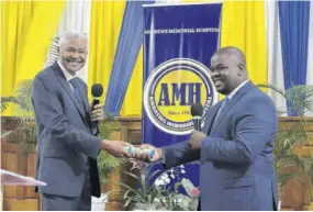  ?? ?? Dr Patric Rutherford (left), immediate former president and CEO of Andrews Memorial Hospital, passes the baton to his successor, Donmayne Gyles, during the service of inaugurati­on and installati­on at Andrews Memorial Seventh-day Adventist Church in St Andrew on Saturday, May 13, 2023.