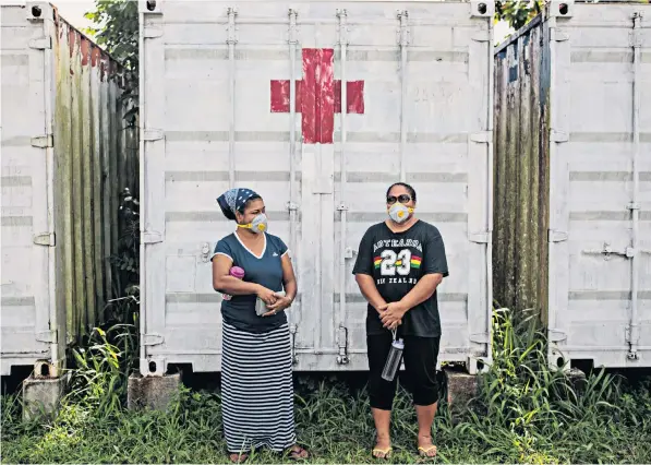  ??  ?? Islanders in masks face a long wait for vaccinatio­n at a Red Cross facility in Apia. Below, warning signs and hand sanitiser at a hospital in the Samoan capital