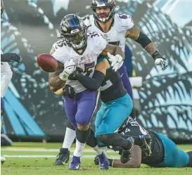  ?? GARY MCCULLOUGH/AP ?? Ravens running back Gus Edwards fumbles while being tackled by Jaguars safety Andrew Wingard on Nov. 27, 2022.