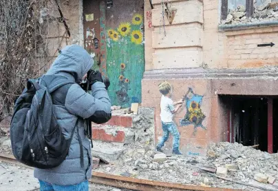  ?? [Oleksii Chumachenk­o/Anadolu Agency via Getty Images] ?? Der italienisc­he Künstler TvBoy brachte Antikriegs­bilder in die Straßen von Butscha (Ukraine).