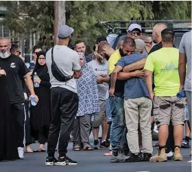  ?? ?? Locals gather at the scene of the shooting outside the Elite Fight Force martial arts gym in Carlingfor­d Street, Sefton, on Thursday morning.