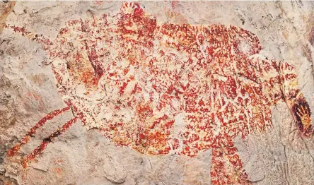  ??  ?? Scientists say the red silhouette of a bull-like beast is the oldest known example of animal art, dated to a minimum of 40,000 years ago.