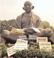  ?? — PRITAM BANDYOPADH­YAY ?? Placards placed around Mahatma Gandhi’s statue after a protest by BJP MPs against Congress during the Budget Session at Parliament House in New Delhi on Friday.