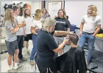  ?? JOURDAN/ THE OKLAHOMAN] ?? Jaxson Walker gets his hair cut as his Davenport teammates watch on Tuesday. The players' hair was donated. [CAMERON