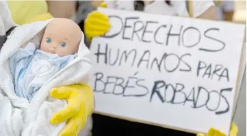  ??  ?? Demonstrat­ors hold baby dolls and placards reading ‘Human rights for stolen babies’ outside a provincial court in Madrid, on the first day of the first trial over thousands of suspected cases of babies stolen from their mothers during the Franco era. — AFP photo
