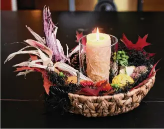  ?? Photos by Chona Kasinger/For the Washington Post ?? Starting with a flat-bottom basket, create a centerpiec­e with gourds and other natural embellishm­ents by arranging them around a beeswax candle.