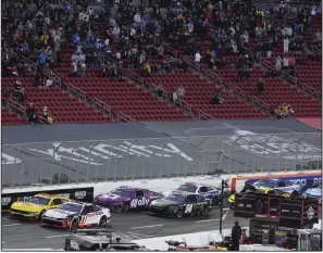  ?? (AP/Mark J. Terrill) ?? Cars race during the NASCAR Busch Light Clash at the Coliseum on Saturday night at the Los Angeles Memorial Coliseum. Denny Hamlin (11) won the race, which was moved up from today to avoid a dangerous “Pineapple Express” storm headed toward California.