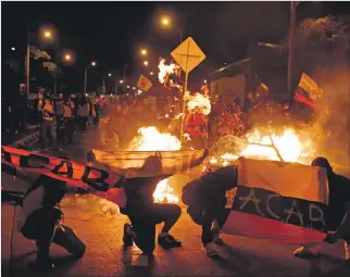  ?? ERNESTO GUZMÁN / EFE ?? Cali. Manifestan­tes muestran banderas de Colombia mientras queman objetos en señal de protesta.