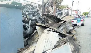  ?? PHOTO BY HOPETON BUCKNOR ?? Sheets of scorched zinc lie outside the premises of John John Auto on Hart Street in Montego Bay, which was razed by fire on Wednesday night.