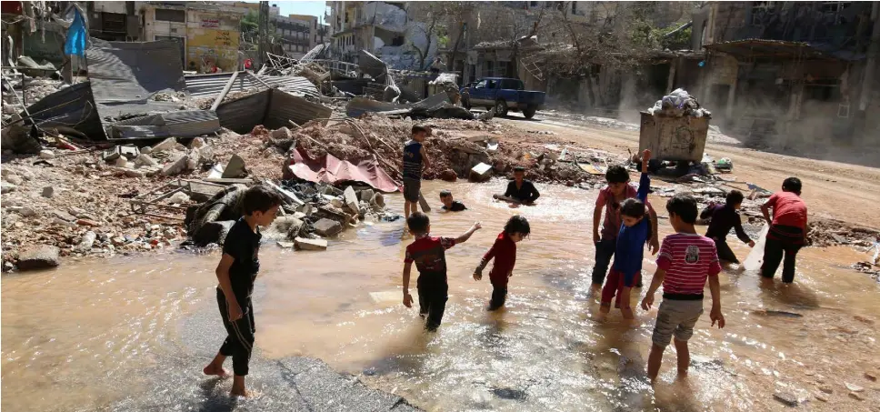  ??  ?? PLAYING IN THE BATTLEGROU­ND: Children splash in the water from a burst water pipe at a site hit by an air strike in Aleppo’s rebel-controlled al-Mashad neighbourh­ood. Photo: Abdalrhman Ismail/Reuters
