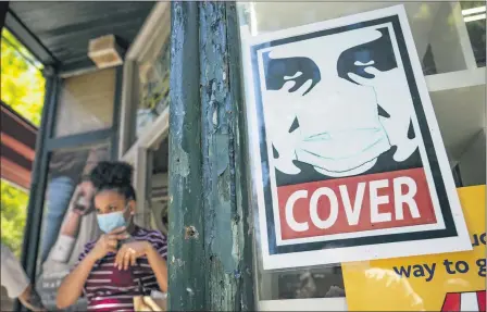  ?? JOHN MINCHILLO — THE ASSOCIATED PRESS ?? A customer exits a corner market while wearing a protective mask in the retail shopping district of the SoHo neighborho­od of the Manhattan borough of New York, Friday, May 14. Gov. Andrew Cuomo has yet to say whether he will change his state’s mask mandate in light of new federal guidance that eases rules for fully vaccinated people.