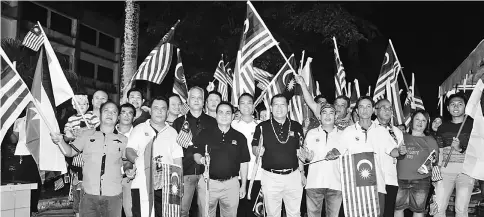  ??  ?? Ugak (front fourth left) leads the flag procession around Kapit town. Kapit informatio­n officer Garai Entili is on his right.