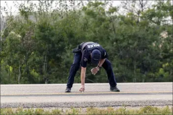  ?? HEYWOOD YU — THE CANADIAN PRESS VIA ASSOCIATED PRESS ?? A Royal Canadian Mounted Police officer lays down a marker on a road outside Rosthern, Saskatchew­an, on Wednesday. Canadian police arrested Myles Sanderson, the second suspect in the stabbing deaths of multiple people in Saskatchew­an, after a three-day manhunt that also yielded the body of his brother fellow suspect, Damien Sanderson.