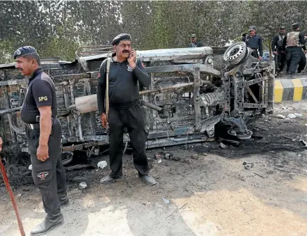  ?? PHOTO: REUTERS ?? Policemen gather after an angry mob torched a police van during a protest yesterday following the suicide blast at the tomb of a Sufi saint in Pakistan’s southern Sindh province.