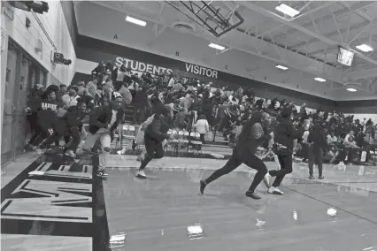  ?? KARA HAWLEY/ROCKFORD REGISTER STAR ?? Students, parents and fans run across the gymnasium floor during a basketball game Wednesday at Auburn High after police say a loud noise was mistaken for gunfire. The game between Auburn and Guilford high schools did not finish.