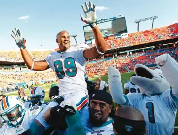  ?? (Joe Skipper/reuters) ?? MIAMI DOLPHINS linebacker Jason Taylor is carried off the field by teammates after their 19-17 home upset over the New York Jets Sunday. Taylor, who was the NFL’S active sack leader, brought the curtain down on his 15-year NFL career after Sunday’s...