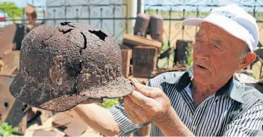  ?? AP/ /THANASSIS STAVRAKIS ?? Vitaly Danilkin holds up memorabili­a and war-related artifacts. Danilkin takes care for a cemetery some 40 miles northwest of Volgograd in Rossoshka, for German soldiers who perished at Stalingrad and nearby Rostov-on-Don, as well as a Soviet cemetery.