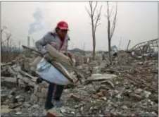  ?? NG HAN GUAN — THE ASSOCIATED PRESS FILE ?? In this file photo taken Saturday a scrap collector gathers materials in a demolished neighborho­od near a chimney spewing smoke in Beijing, China.