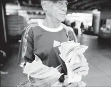  ??  ?? A street vendor counts bolivar notes near Venezuela’s Central Bank in Caracas, Venezuela December 16, 2016.