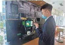  ?? PROVIDED TO CHINA DAILY ?? An employee buys Starbucks coffee at a vending machine next to his workspace in Beijing.