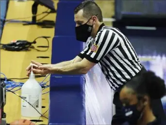  ?? Associated Press ?? SIGN OF THE TIMES During a stop in play during the Connecticu­t-Xavier game Saturday in Storrs, Conn., an official avails himself of a courtside hand sanitizer station.