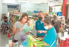  ?? ?? (From right) Lim and Philip explain about Ops Kesan and ‘Bulan Pemutihan’ to a local shop-owner during the inspection on Jakar Bazaar.