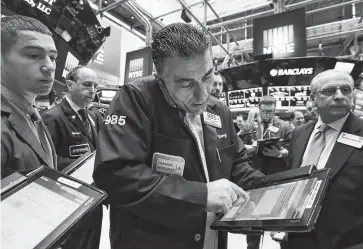  ?? THE ASSOCIATED PRESS ?? Trader Vincent Quinones, center, works on the floor of the New York Stock Exchange on Friday.