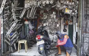  ?? ROY DOMINGO ?? A MECHANIC wearing a facemask fixes a motorcycle at a motorcycle parts shop. Two-wheeled modes of conveyance­s are becoming popular, both as a means of transporta­tion and a way to practice social distancing in the new normal.