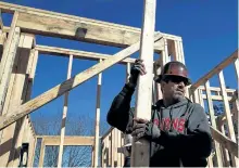  ?? GETTY FILES ?? Above, a worker carries lumber as he builds a new home. Based on a sixmonth rolling average, CMHC said there were 211,342 new constructi­on starts in March on an annualized basis, up from 205,521 a month earlier.