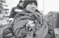  ?? Andreea Alexandru / Associated Press ?? A Ukrainian refugee holds her pet cat at the Romanian-Ukrainian border. Thousands are traveling light while escaping the conflict.