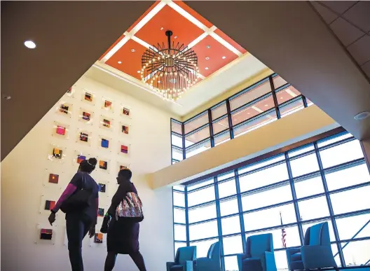  ??  ?? Nurses walk past a family waiting room at Presbyteri­an Santa Fe Medical Center. Work by a local artist adorns the wall.